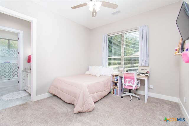 carpeted bedroom featuring ensuite bath, multiple windows, and ceiling fan