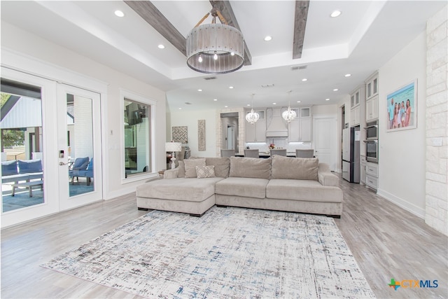 living room featuring light wood-type flooring, beamed ceiling, and a raised ceiling