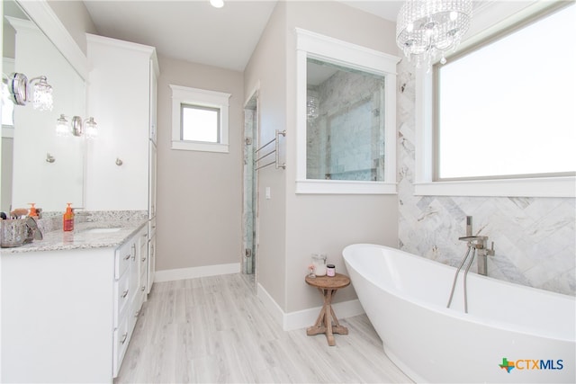 bathroom featuring shower with separate bathtub, vanity, an inviting chandelier, and hardwood / wood-style flooring