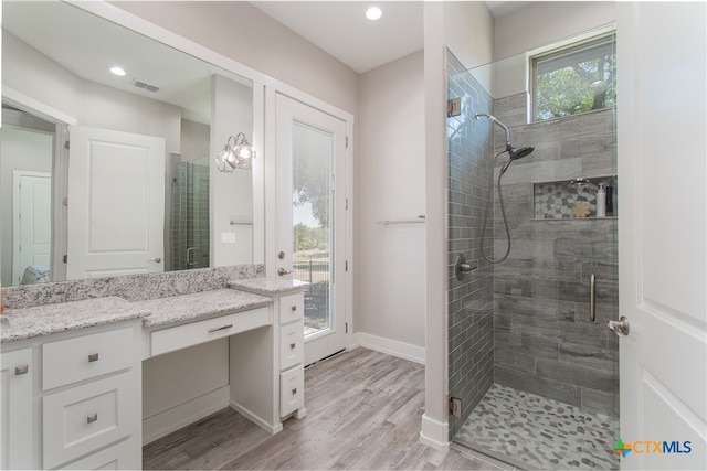 bathroom featuring hardwood / wood-style floors, vanity, and a shower with shower door