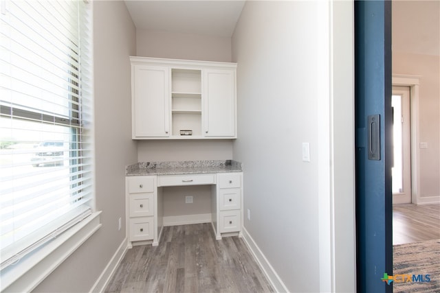 unfurnished office with light wood-type flooring and built in desk