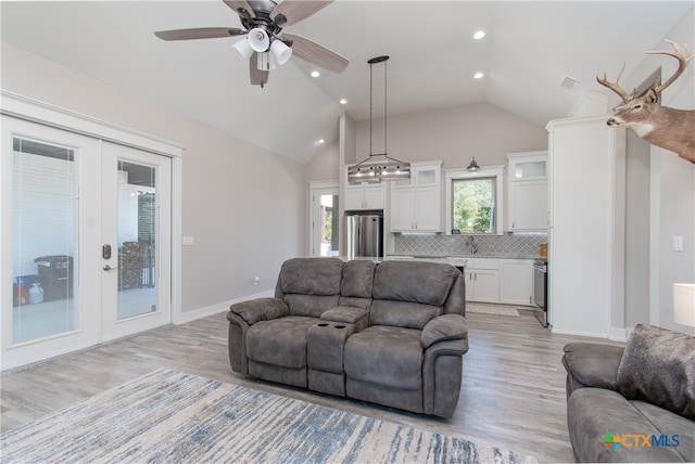 living room with french doors, light hardwood / wood-style floors, and vaulted ceiling