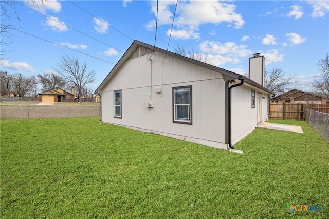 back of property featuring a lawn, a fenced backyard, and a chimney