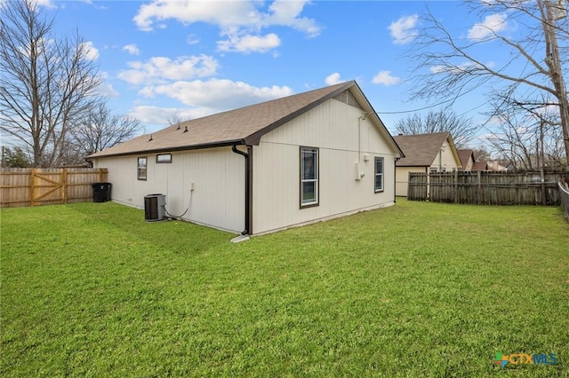 rear view of house featuring cooling unit, a fenced backyard, and a lawn