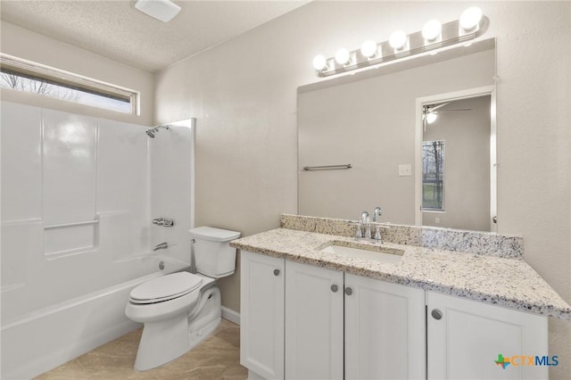 full bathroom with vanity, washtub / shower combination, ceiling fan, a textured ceiling, and toilet