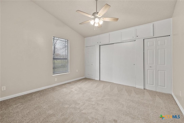 unfurnished bedroom with light carpet, a ceiling fan, a closet, baseboards, and vaulted ceiling