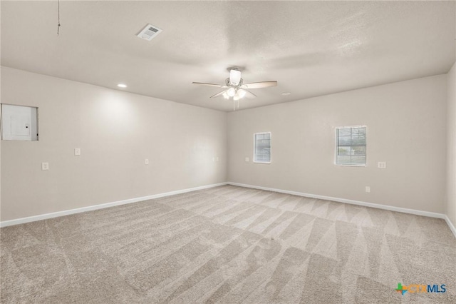 unfurnished room with baseboards, visible vents, electric panel, ceiling fan, and light colored carpet