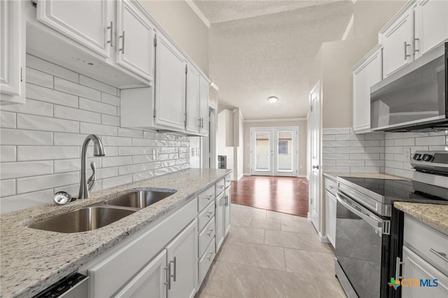 kitchen featuring a sink, a textured ceiling, appliances with stainless steel finishes, white cabinets, and crown molding