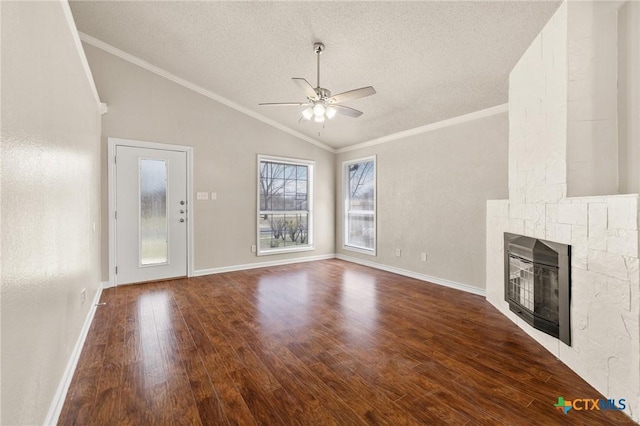 unfurnished living room featuring wood finished floors, lofted ceiling, a fireplace, ornamental molding, and ceiling fan