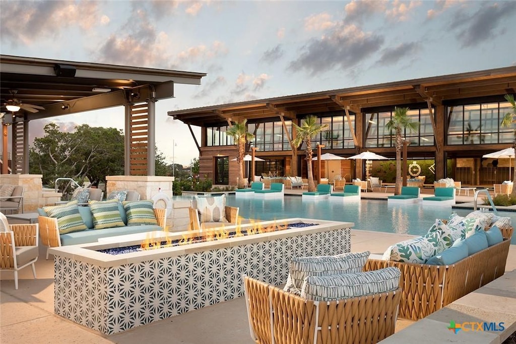 pool with a patio area and an outdoor living space with a fire pit