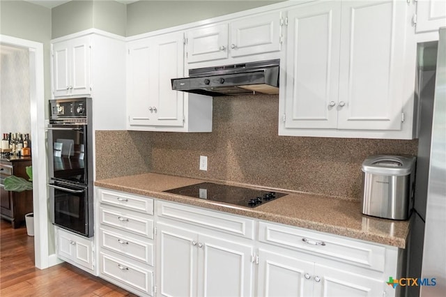 401 Hampshire St, Victoria, TX 77904 - kitchen featuring black appliances, under cabinet range hood, white cabinetry, and decorative backsplash