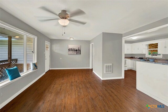 1210 Old Martindale Rd, San Marcos, TX 78666 - unfurnished living room with baseboards, dark wood-style flooring, visible vents, and a ceiling fan