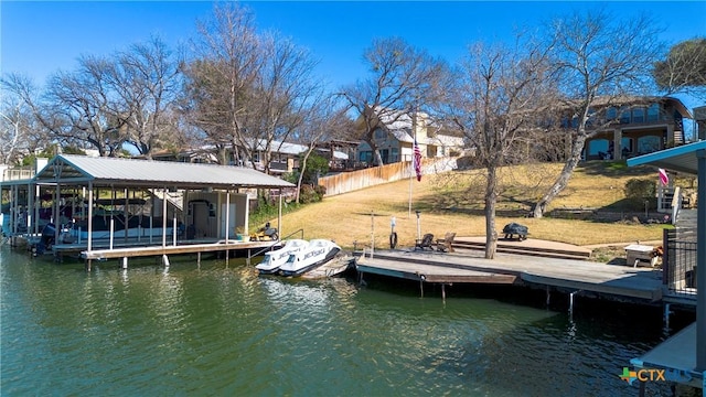 dock area featuring a water view, a lawn, and fence