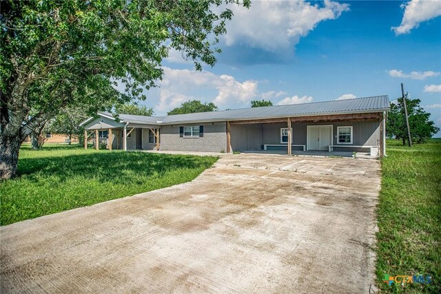 248 Park Rd, Port Lavaca, TX 77979 - ranch-style house with driveway, a front yard, a carport, metal roof, and covered porch