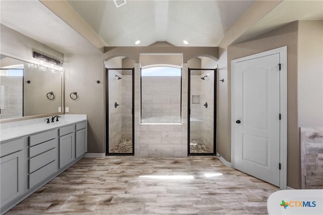 bathroom with lofted ceiling, wood finished floors, a textured ceiling, vanity, and a shower stall