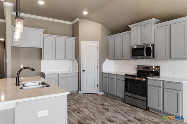 kitchen featuring gray cabinets, light countertops, hanging light fixtures, appliances with stainless steel finishes, and a sink