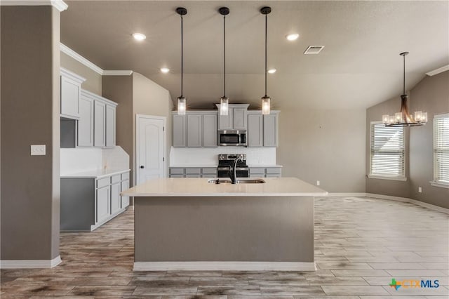 kitchen featuring visible vents, light countertops, stainless steel microwave, and a center island with sink