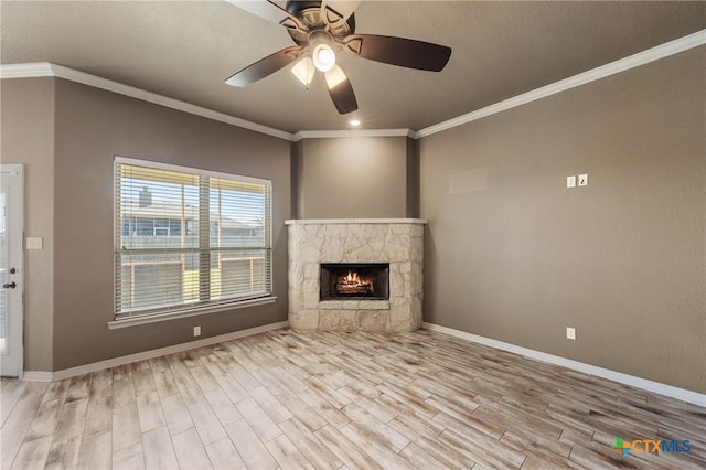 unfurnished living room with ceiling fan, light wood-style flooring, a fireplace, baseboards, and crown molding