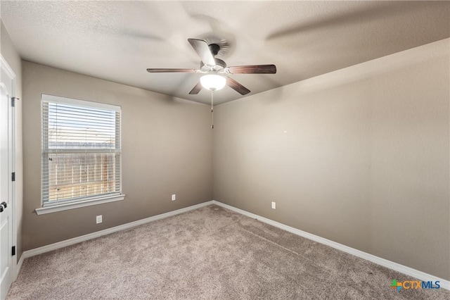 spare room featuring a ceiling fan, light carpet, a textured ceiling, and baseboards