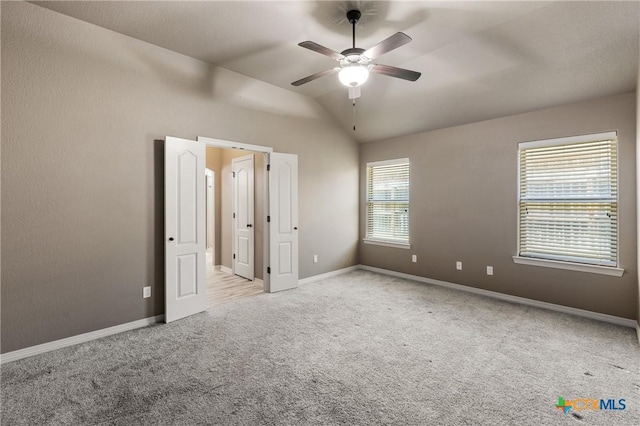 unfurnished bedroom with lofted ceiling, light carpet, ceiling fan, and baseboards