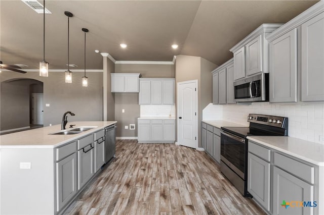 kitchen featuring a ceiling fan, a kitchen island with sink, stainless steel appliances, light countertops, and a sink