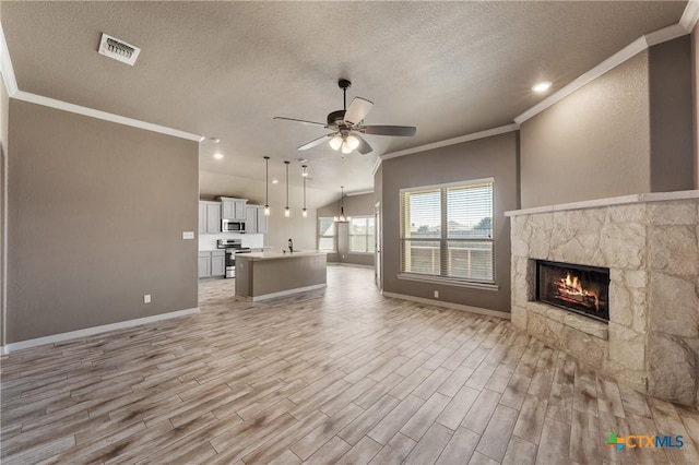 unfurnished living room featuring visible vents, light wood-style flooring, ceiling fan, crown molding, and a fireplace