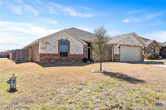 ranch-style home featuring a front yard, brick siding, fence, and an attached garage