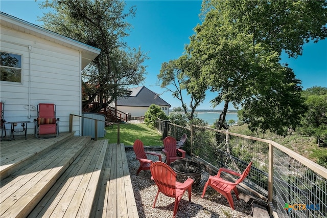 wooden deck featuring fence, a water view, an outdoor fire pit, a yard, and stairway