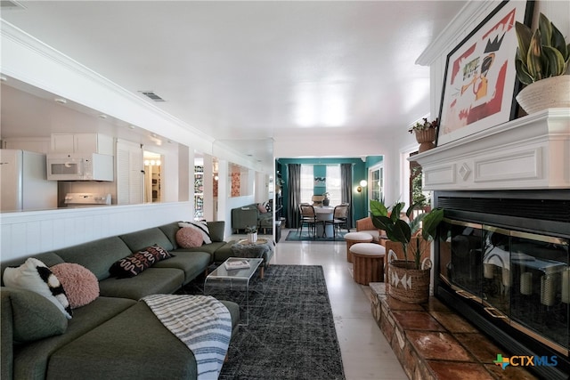 living room featuring visible vents, ornamental molding, and a glass covered fireplace