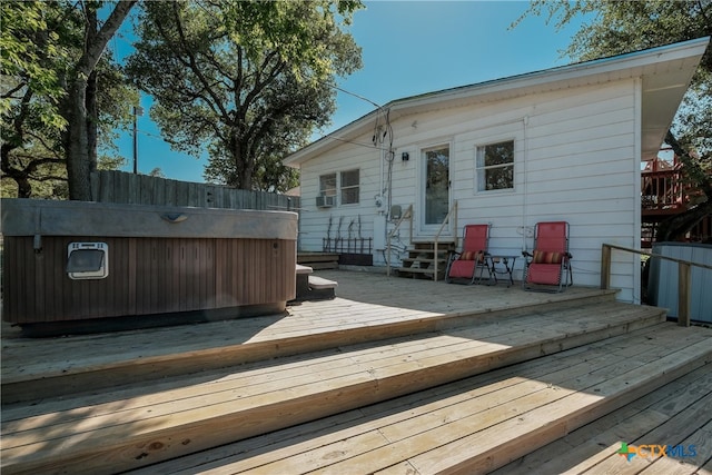 rear view of house with a hot tub, a wooden deck, and entry steps
