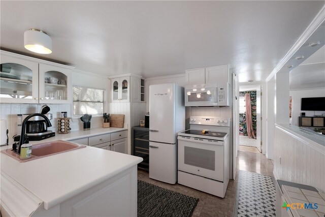 kitchen featuring white appliances, white cabinets, glass insert cabinets, and a sink