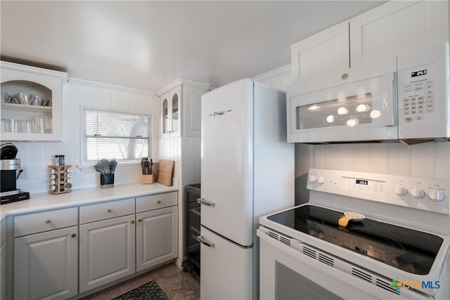 kitchen featuring light countertops, white cabinetry, white appliances, and glass insert cabinets