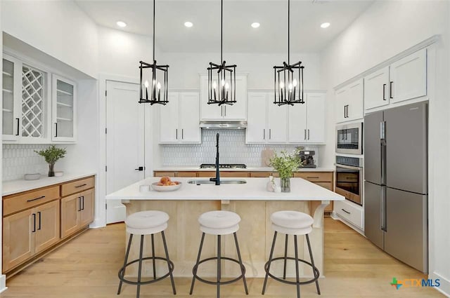 kitchen featuring white cabinetry, light wood-type flooring, a center island with sink, and appliances with stainless steel finishes