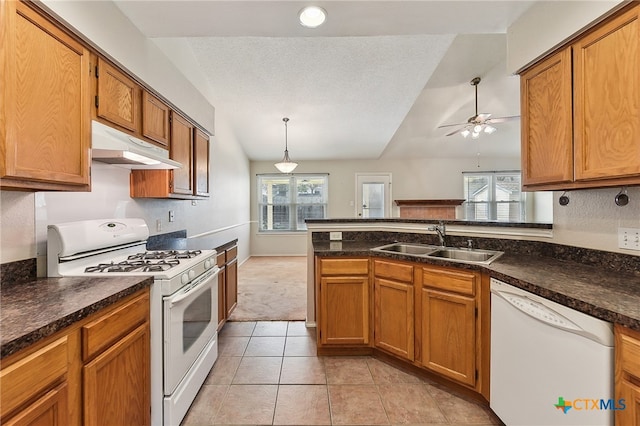 kitchen featuring under cabinet range hood, brown cabinets, white appliances, and a sink