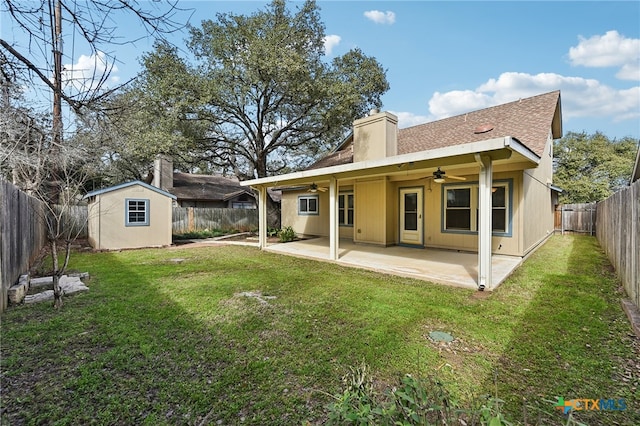 back of property with a patio, an outbuilding, a fenced backyard, ceiling fan, and a chimney