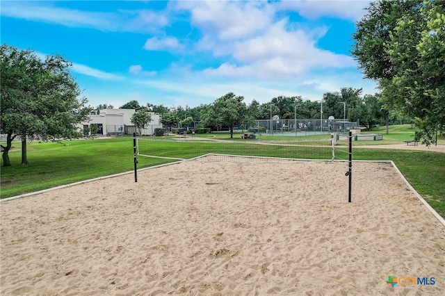 view of property's community featuring volleyball court, a lawn, and fence