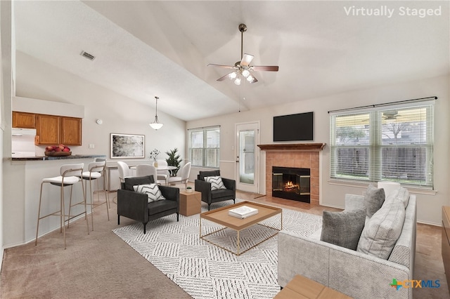 living room featuring a ceiling fan, visible vents, high vaulted ceiling, a fireplace, and light colored carpet