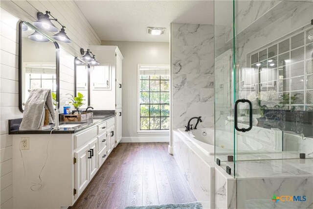 507 Hackberry Bnd, Port Lavaca, TX 77979 - full bathroom featuring a garden tub, double vanity, wood finished floors, a marble finish shower, and baseboards