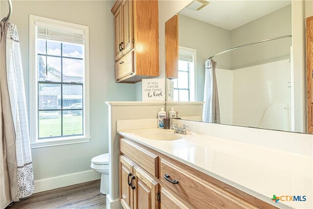 507 Hackberry Bnd, Port Lavaca, TX 77979 - bathroom featuring wood finished floors, toilet, vanity, baseboards, and curtained shower