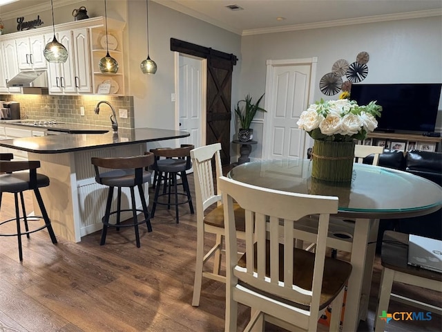507 Hackberry Bnd, Port Lavaca, TX 77979 - dining area with a barn door, dark wood-type flooring, and crown molding
