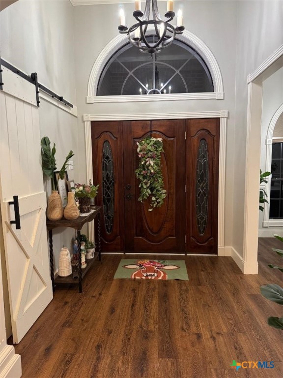 507 Hackberry Bnd, Port Lavaca, TX 77979 - entrance foyer featuring a chandelier, a barn door, wood finished floors, and baseboards