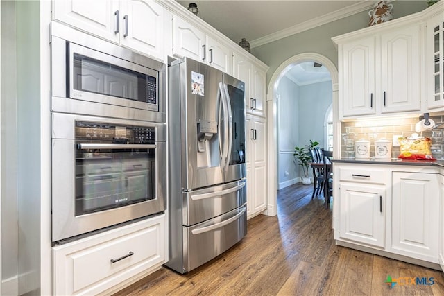 507 Hackberry Bnd, Port Lavaca, TX 77979 - kitchen featuring appliances with stainless steel finishes, crown molding, tasteful backsplash, white cabinets, and dark wood-style flooring