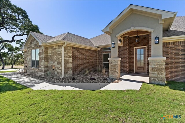 4231 Cold Springs Dr, Copperas Cove, TX 76539 - doorway to property featuring brick siding, a yard, an attached garage, and roof with shingles