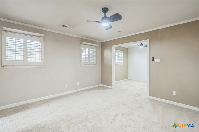 carpeted spare room with ceiling fan, a healthy amount of sunlight, and crown molding