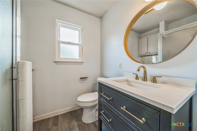 bathroom featuring vanity, hardwood / wood-style flooring, toilet, and a shower with door