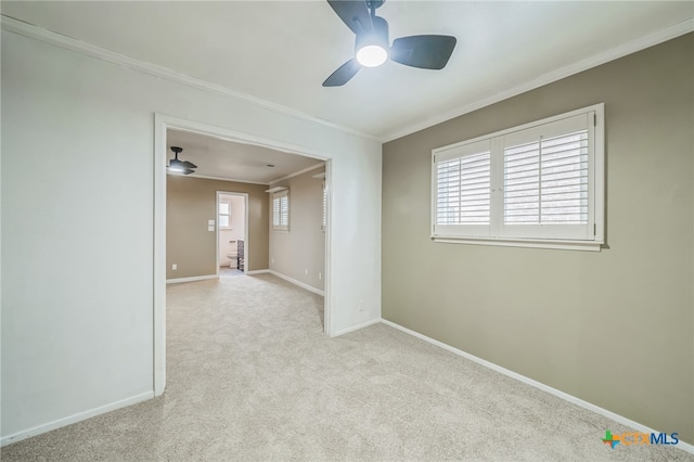 carpeted spare room featuring ceiling fan, a healthy amount of sunlight, and crown molding