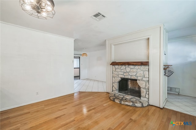 unfurnished living room with a stone fireplace and light wood-type flooring