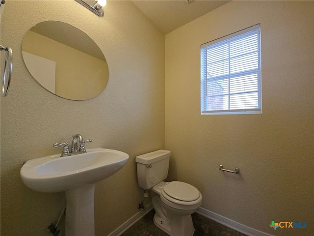 half bath featuring tile patterned flooring, baseboards, vaulted ceiling, and toilet