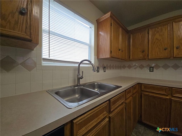 kitchen featuring brown cabinetry, decorative backsplash, light countertops, and a sink