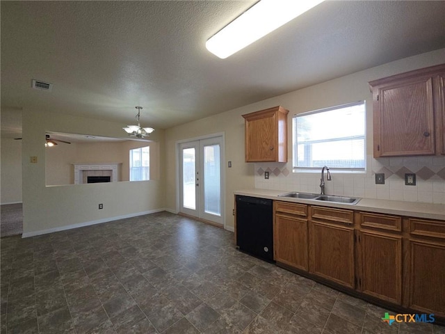 kitchen featuring black dishwasher, tasteful backsplash, visible vents, brown cabinetry, and a sink